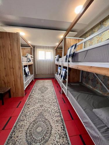 a room with two bunk beds and a red tile floor at InJoy hostel in Shymkent
