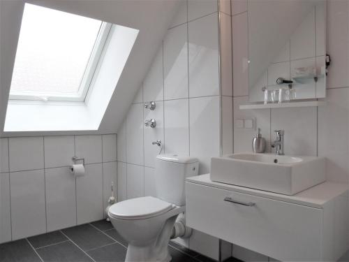 a white bathroom with a toilet and a sink at Hotel Brehm in Würzburg
