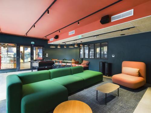 a living room with a green couch and chairs at Hife Gentilly Paris Sud Porte d'Italie in Gentilly