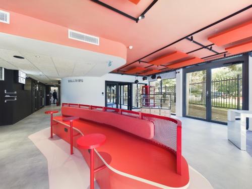 a red bench in a building with windows at Hife Gentilly Paris Sud Porte d'Italie in Gentilly
