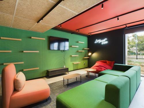 a living room with green and orange furniture at Hife Gentilly Paris Sud Porte d'Italie in Gentilly