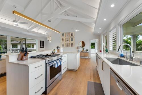 a kitchen with white cabinets and a stove top oven at Ka Hale Olu at Anini Beach TVNC#4218 in Kilauea