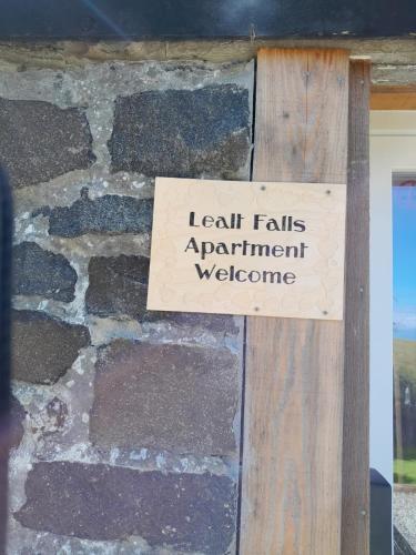un cartel en una pared de piedra que diga "Leah Falls" apartamento bienvenido en Lealt Falls Apartment en Culnacnoc