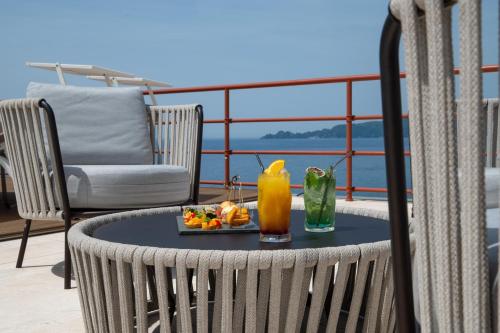 a table with a drink and a plate of food on a balcony at Grand Hotel Torre Fara in Chiavari