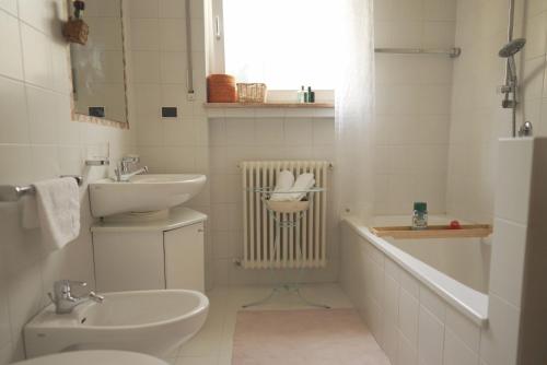 a white bathroom with a sink and a toilet at Stylish hideout - mountain view in Brixen