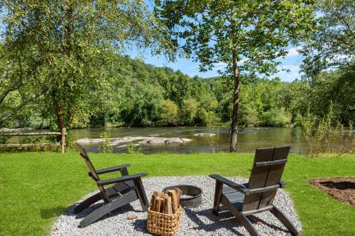two chairs and a picnic table next to a river at Asheville River Cabins in Arden