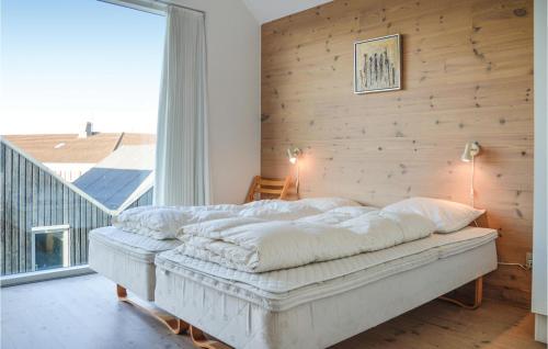 ein Schlafzimmer mit einem Bett mit einer Holzwand in der Unterkunft 2 Bedroom Gorgeous Home In Hvide Sande in Hvide Sande