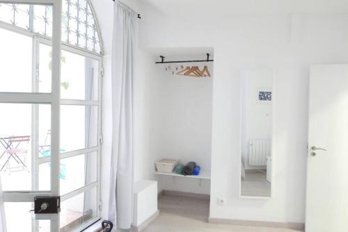 um quarto branco com uma janela e um espelho em Alfama Terrace Apartment em Lisboa