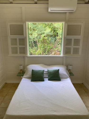 ein Schlafzimmer mit einem großen weißen Bett und einem Fenster in der Unterkunft Kaz’Ary in Sainte-Anne