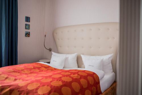 a bedroom with a bed with a red and orange blanket at Romantikhotel Rebstock art & design in Kehl am Rhein