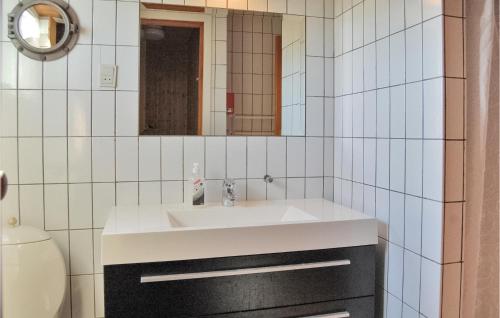 uma casa de banho com um lavatório branco e um espelho. em Nice Home In Hvide Sande With 3 Bedrooms, Sauna And Wifi em Nørre Lyngvig