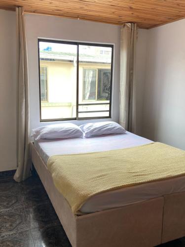 Cama en habitación con ventana en Acogedor Apartamento céntrico I, en Armenia