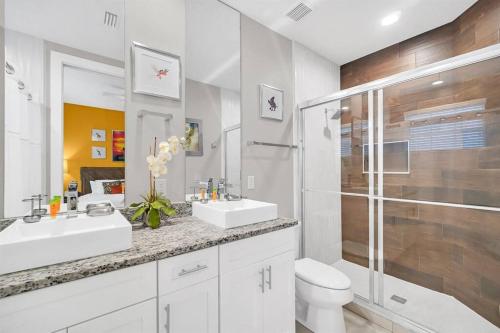 a white bathroom with two sinks and a shower at Magical Residence Resort, 5 min Disney in Orlando