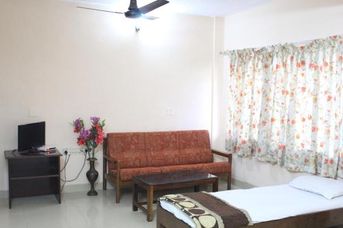 a room with a bed and a couch and a tv at Hotel Silver Sand in Trivandrum