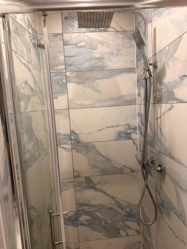 a shower with a glass door in a bathroom at Lovely Hillingdon Family Holiday Home - 6 bedrooms in Ickenham