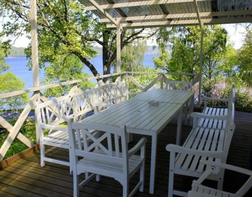 einen Holztisch und Stühle auf einer Terrasse mit Wasser in der Unterkunft Paradiesische Villa mit Seeblick, großem Wintergarten und Außenterrasse mit Grill in Ulricehamn