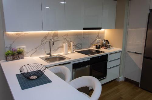 a kitchen with white cabinets and a sink and a table at DIAMOND OF SKOPJE JB in Skopje