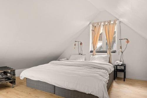 a bedroom with a bed with white sheets and a window at Dinbnb Homes I 4-apartment House in Idyllic Location in Bergen