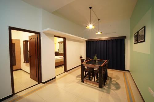 sala de estar con mesa y dormitorio en Ganga's Sri Balaji Cottage, en Ooty