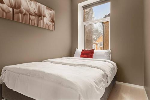 um quarto com uma grande cama branca e uma janela em Dinbnb Apartments I New 2023 I 600m to Bryggen em Bergen