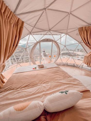 a bed in a tent with a large window at ม่อนชาพาเพลิน ม่อนแจ่ม Monchapaplearn Monjam in Mon Jam
