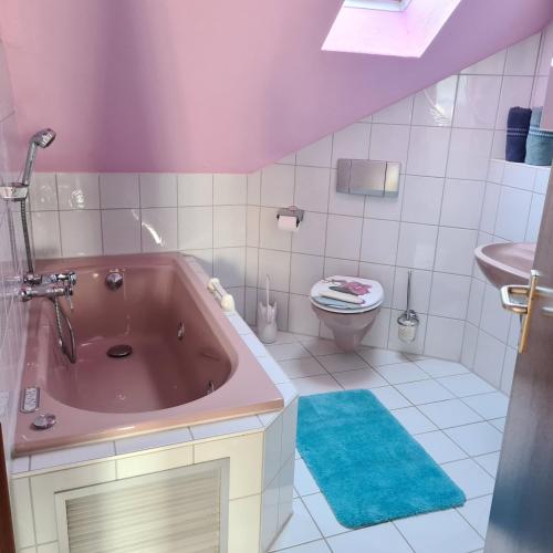 a bathroom with a pink tub and a toilet at Ferienwohnung Sahrmann in Mistelgau