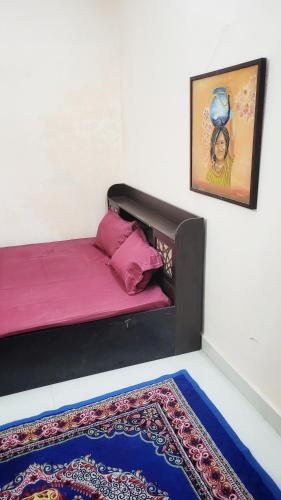 een kamer met een bed met roze lakens en een tapijt bij Advaitam in Ujjain