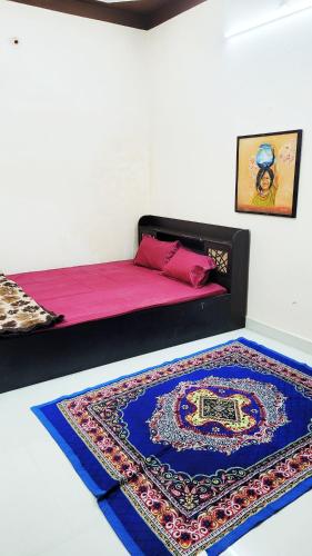 a bedroom with a bed with a rug on the floor at Advaitam in Ujjain