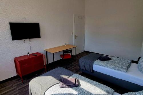 Pokój z 2 łóżkami i stołem z telewizorem w obiekcie Apartment ROTER FADEN w Hanowerze