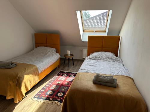 a attic bedroom with two beds and a window at Apartament Oksford 2 in Okszów