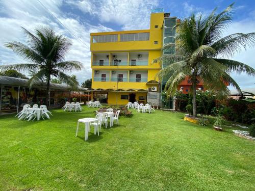 un hôtel avec des tables et des chaises blanches dans la cour dans l'établissement Chesmar Plaza Hotel, à Vera Cruz de Itaparica