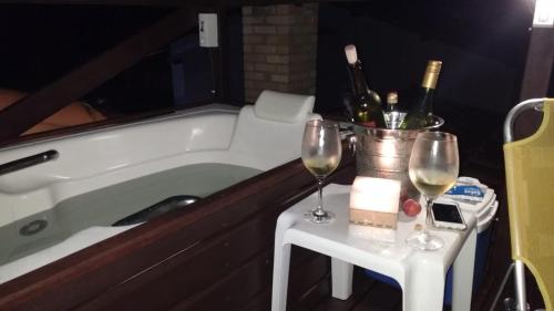 a bath tub with two glasses of wine on a table at Pousada Nascente do Pirahy in Piraí