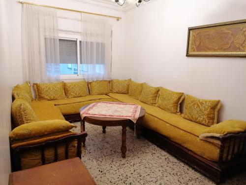 a living room with a yellow couch and a table at Apartamento renovado céntrico zona Hamama solo familias in Tetouan