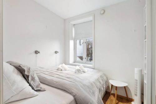 een witte slaapkamer met een groot bed en een raam bij Dinbnb Apartments I Cozy 1-Bedroom Nestled in the Heart of Bergen in Bergen