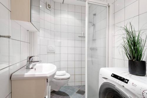 a bathroom with a sink and a washing machine at Dinbnb Apartments I Cozy 1-Bedroom Nestled in the Heart of Bergen in Bergen