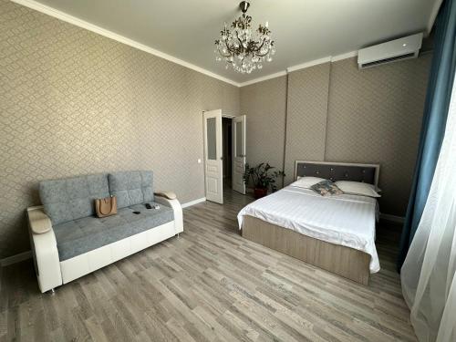 - une chambre avec un lit, un canapé et un lustre dans l'établissement ExpoNewLife2, à Astana