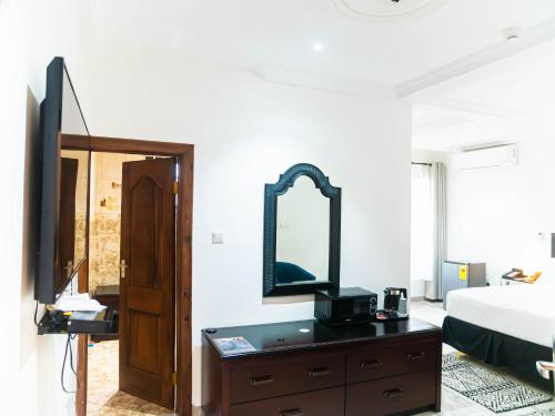 a bedroom with a bed and a dresser with a mirror at KoKo Palm Inn in Accra
