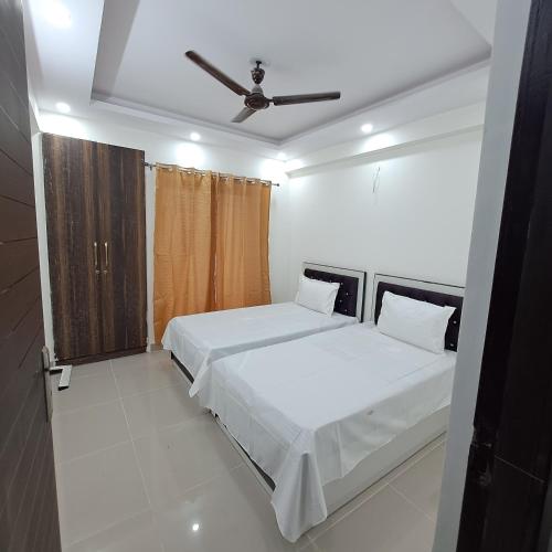 a bedroom with two beds and a ceiling fan at Gokul 2 BHK Entire Flat, Bharat City, Teela Mod, Nr Hindon Airport ,Bhopura , Ghaziabad in Ghaziabad