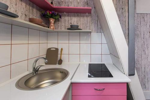 eine Küche mit einem Waschbecken und einem rosa Schrank in der Unterkunft Sleep&Go in Lwiw
