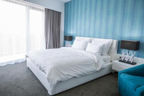 a bedroom with a white bed and a blue wall at Hotel Tempo in Târgu-Mureş