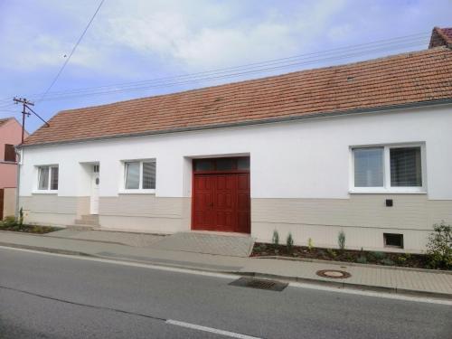 una casa blanca con una puerta roja en una calle en NaKonci, en Vacenovice