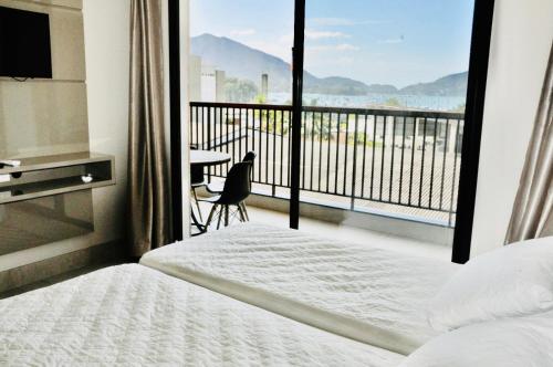 a bedroom with a bed and a balcony with a table at Apartamento Alto Padrão Ubatuba in Ubatuba