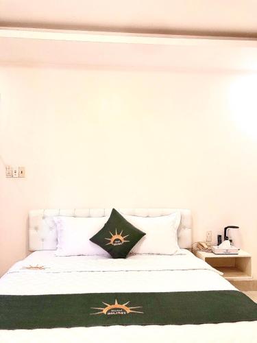 a white bed with a green and gold blanket on it at Holiday Hotel 2 in An Khê