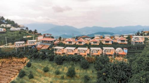a group of houses on a hill with mountains in the background at ม่อนชาพาเพลิน ม่อนแจ่ม Monchapaplearn Monjam in Mon Jam
