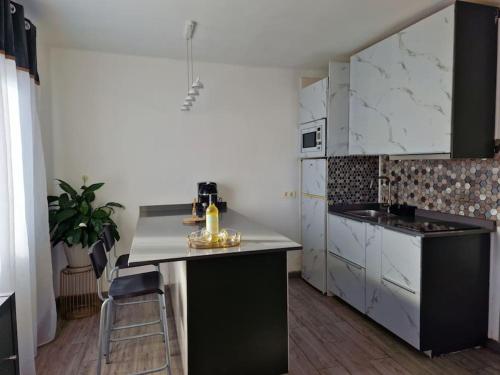 a kitchen with white cabinets and a black and white counter at RockBeach bungalow in Costa Teguise