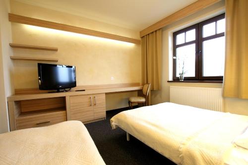 a bedroom with a bed and a tv on a desk at Absolwent in Zieleniec