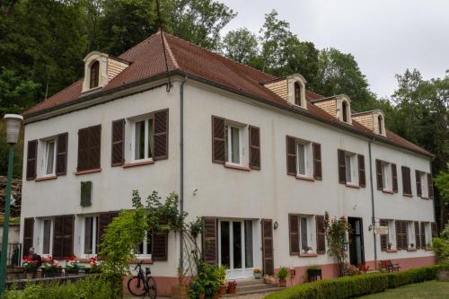 une grande maison blanche avec des fenêtres à volets marron dans l'établissement Moulin de Belle Isle, à Bèze