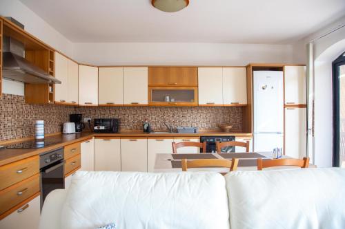 une cuisine avec des placards blancs et une table avec des chaises dans l'établissement 2BD Cosy Apartment with Spacious Balcony - Close to Bugibba Beach, à San Pawl il-Baħar