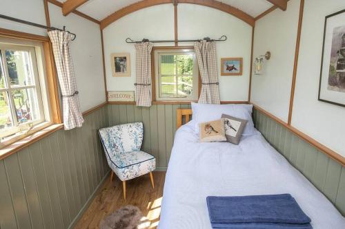 a small bedroom with a bed and a chair at Shepherds Huts Tansy & Ethel in rural Sussex in Arundel