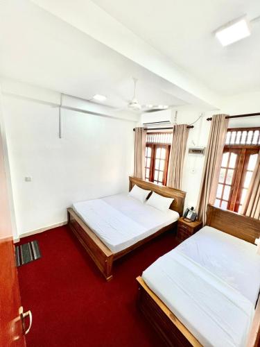 2 camas en una habitación con 2 ventanas en KINGS HOTEL, en Colombo